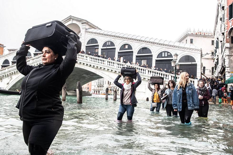 Ihmiset kantoivat matkalaukkujaan tulvaveden valtaamassa Venetsiassa maanantaina.