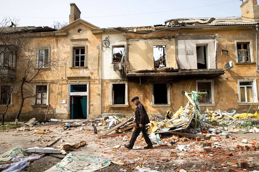 Mikhail Koval walks through the rubble on his own home corners.