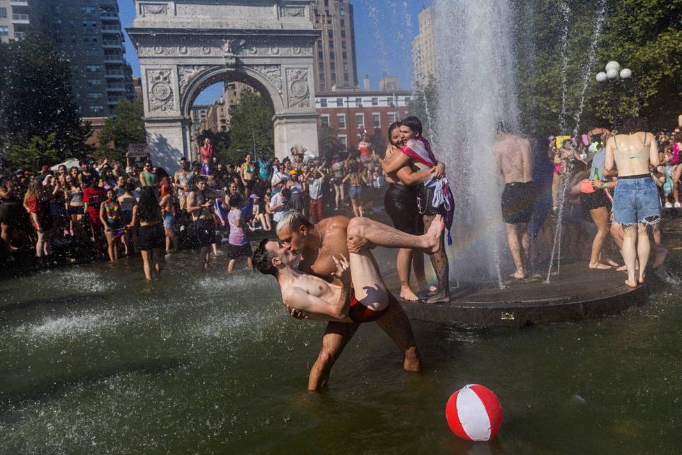 Ihmiset halaavat ja suutelevat suihkulähteessä Washington Square Park -puistossa New Yorkissa.