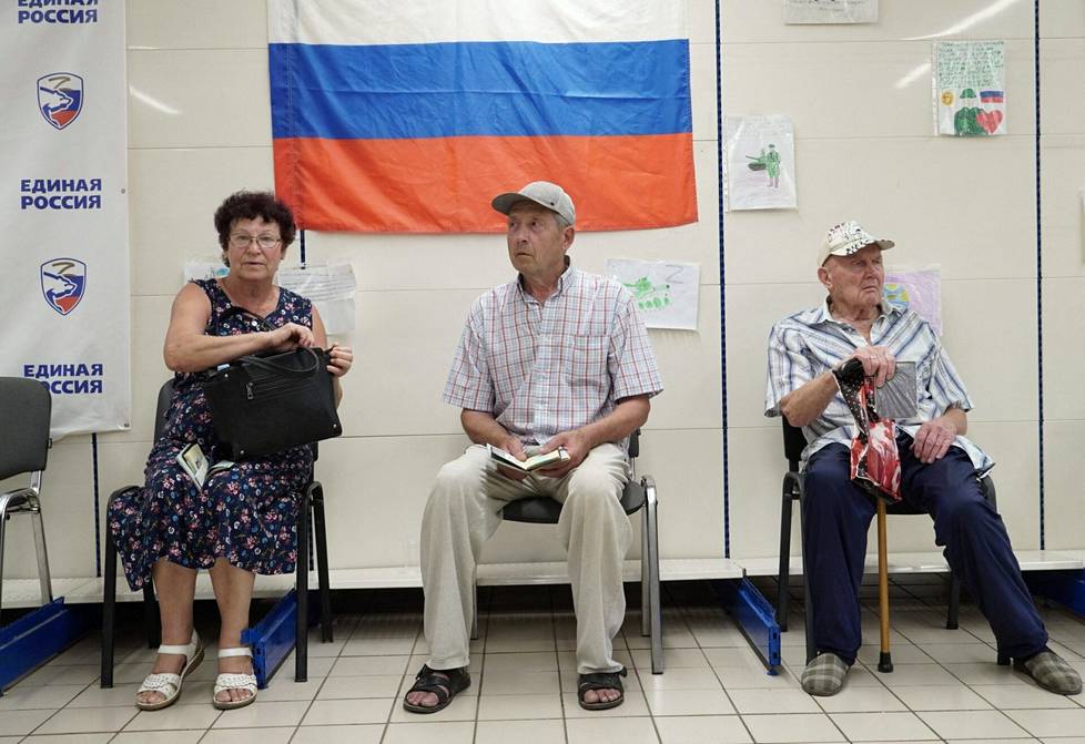 Ukrainan eteläosissa Zaporižžjan alueella sijaitsevan Melitopolin kaupungin asukkaita on saapunut hakemaan ruoka-apua avustuskeskuksesta, jota hallinnoi Venäjän valtapuolue Yhtenäinen Venäjä. Taustalla Venäjän lippu ja Yhtenäinen Venäjä -puolueen logo. Kuva otettu 2. elokuuta.