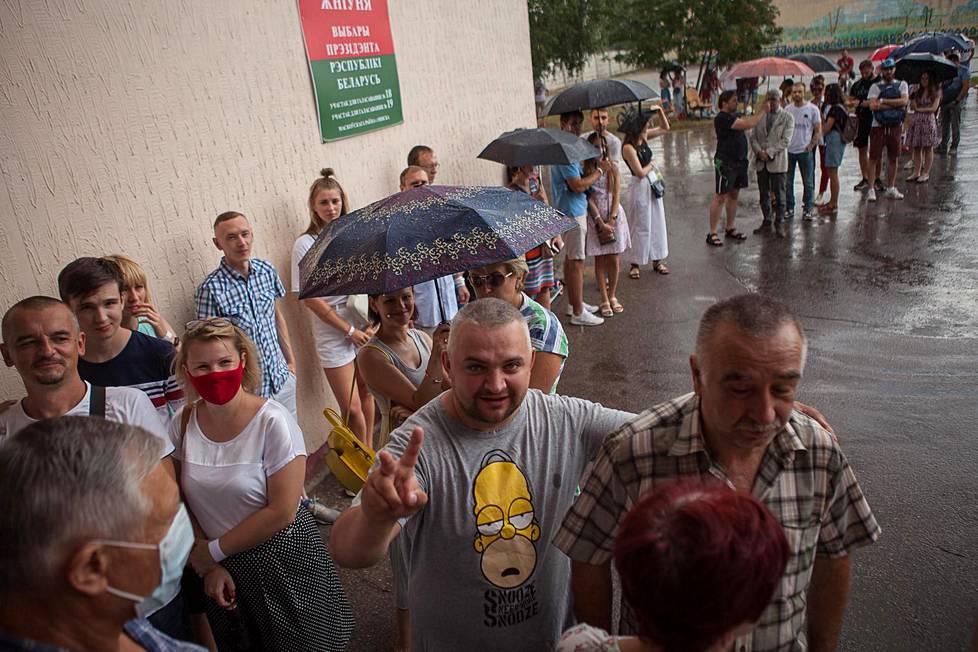 Minskiläiset äänestäjät jonottivat kärsivällisesti koulussa sijainneelle äänestyspaikalle sateesta huolimatta.