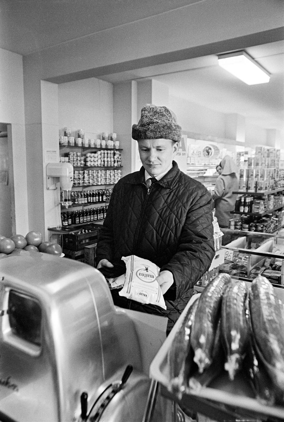 Mies ostaa maitopussin ruokakaupassa 1960-luvulla.