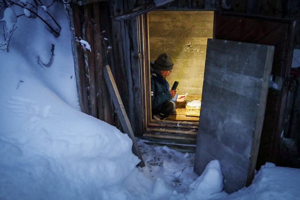 Lumi kätkee sisäänsä pimeän maakellarin. Asemanjohtaja Otso Suominen valaisee purkkeja.