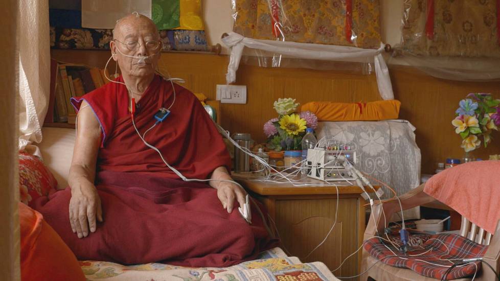 Tashi Namgyal -niminen 86-vuotias munkki on kokenut meditaation harjoittaja, joka osallistui tukdam-tutkimukseen. Tutkimuksessa selvitettiin myös elossa olevien meditoijien aivotoimintaa. Tashi Namgyalia tutkittiin Pohjois-Intiassa vuonna 2019. Kuvakaappaus elokuvasta.