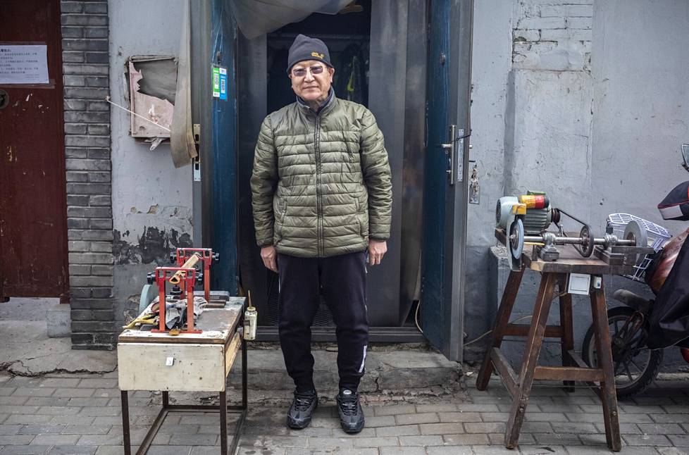 Teroittajamestari Wang Peizhi seisoo työpajansa oven edessä. Työkoneet ovat oven ulkopuolella kujalla. Sisällä on liian vähän tilaa, jotta siellä voisi niitä käyttää.