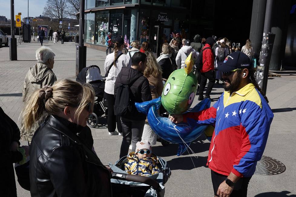 Neea Luokkala (left), eight-month-old Osean Aguilar and Ulises Aguilar queued for free May Day balls in Hakaniemi at Ympyrätalo.