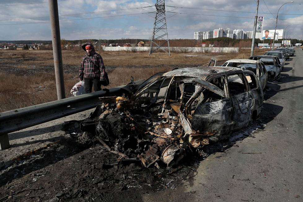 Nainen käveli tuhoutuneen auton ohi Kiovassa.