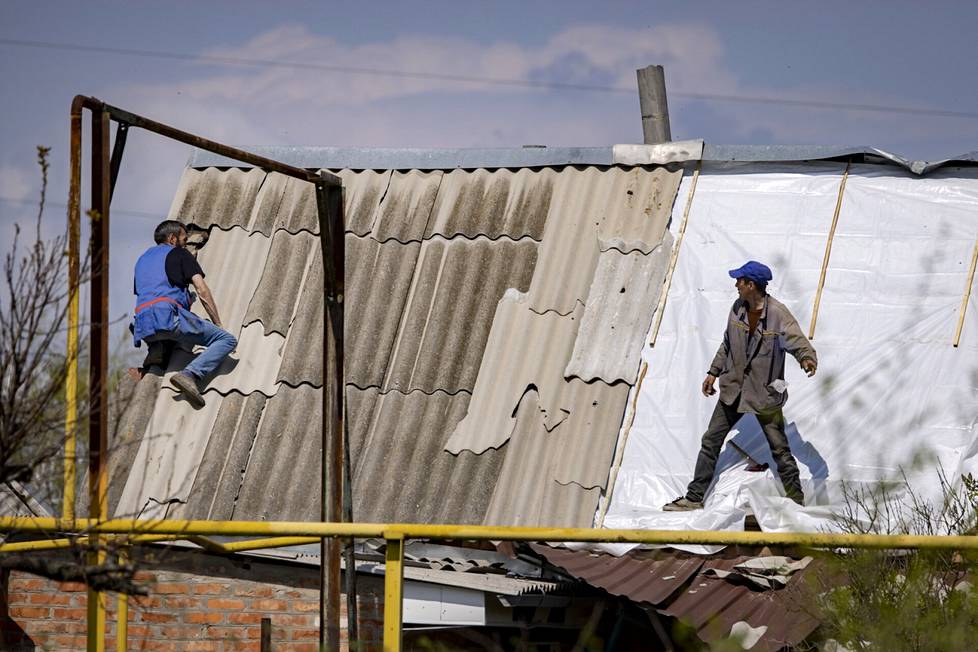 Vapaaehtoiset pressuttivat kattoa Orihivissa. Työ on vaarallista jatkuvien iskujen takia.