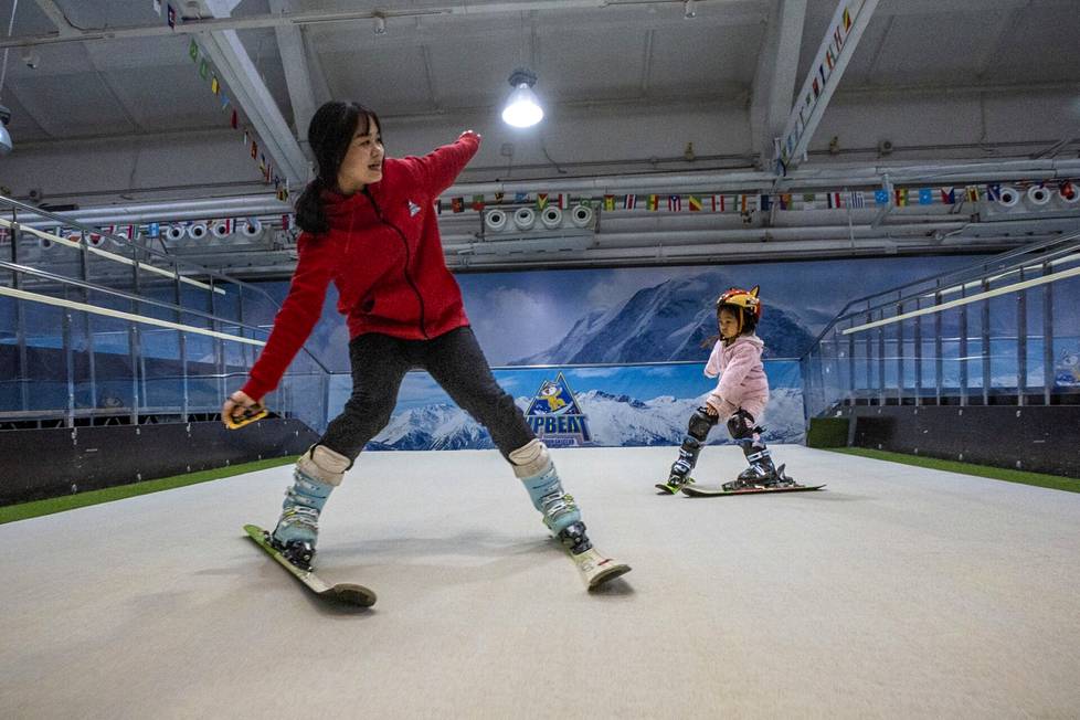 Pekingiläiset luovat suhdetta lumeen. 4-vuotias Yan Ruixi on laskettelusuksilla sisähallissa viidettä kertaa. Laskettelunopettaja neuvoo edessä.