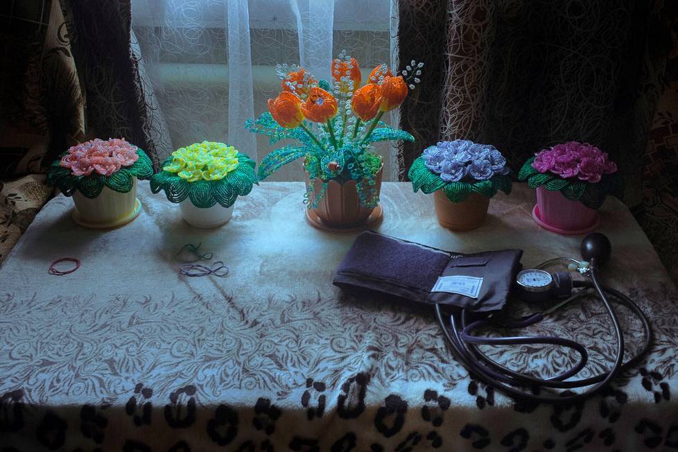 Lyudmila Bugantsova has suffered from heart symptoms.  She makes plastic beads into flower arrangements to calm herself.