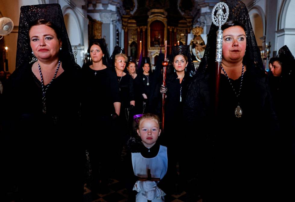 Perinteisiin mantillamekkoihin pukeutuneet naiset odottavat kirkossa osallistuakseen kulkueeseen Rondassa Espanjassa.