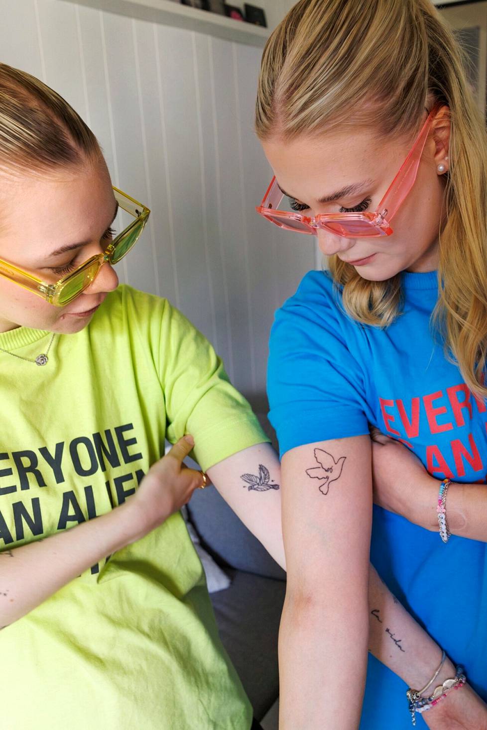 Ella Artevo (left) has 18 Coldplay-related tattoos: among other things, various symbols and texts.  One of them is a friend tattoo with Emma Heikura (right).  The bird tattoo is related to Coldplay's song Magic, which is also the duo's 