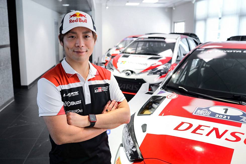 Takamoto Katsuta Toyotan rallitallin tiloissa Jyväskylässä. Vieressä on auto, jolla Sébastien Ogier ajoi viime vuonna Suomen MM-rallissa.