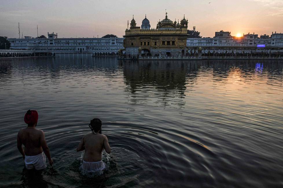 Sikhit kastautuivat Kultaisen temppelin edessä auringon laskiessa Intiassa.