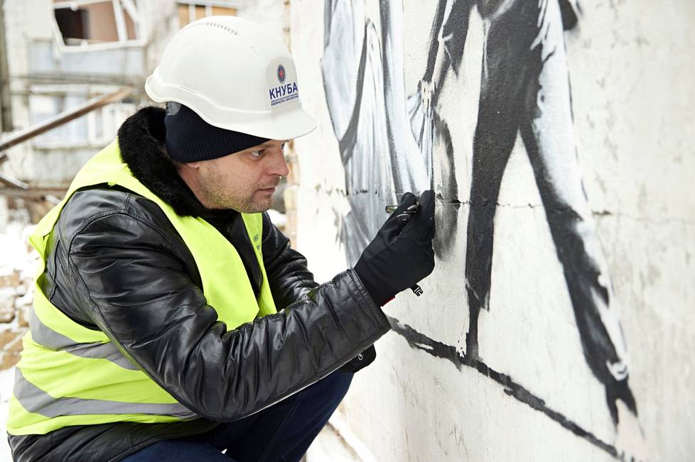 Professori Oleksandr Molodid tutkii Banksyn muraalin kuntoa Borodjankassa. 