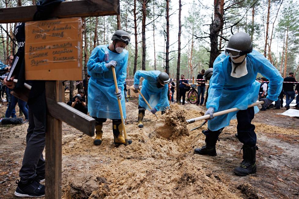 Ukrainalaisviranomaiset kaivoivat hautoja auki mäntymetsässä Izjumissa.