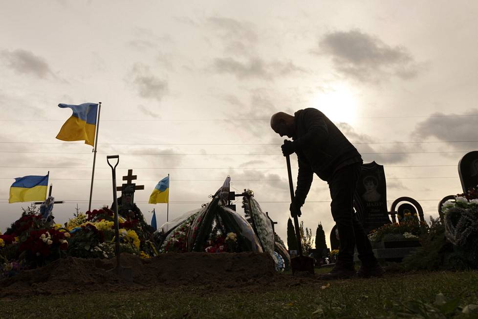 3. lokakuuta, Butša. Venäjän hyökkäyssodassa kaatuneiden ukrainalaissotilaiden hautoja hautausmaalla numero 3. Haudankaivaja lapioi hautaa umpeen. 