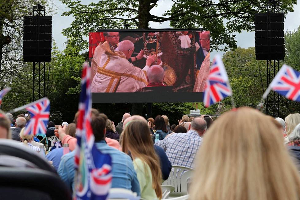 Ihmiset seuraavat puistossa näytöltä, kun kuningas Charles III kruunattiin.