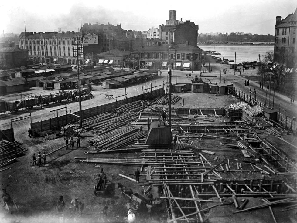Hakaniemen hallin rakennustyömaa noin 1910-luvun alussa. Taustalla näkyvät Eläintarhanlahti ja Siltasaarenkatu, vasemmalle kuvassa jää Hakaniementori. Kuvat 1900-luvun alun ja nykypäivän rakentamisesta näyttävät aikojen muutoksen.