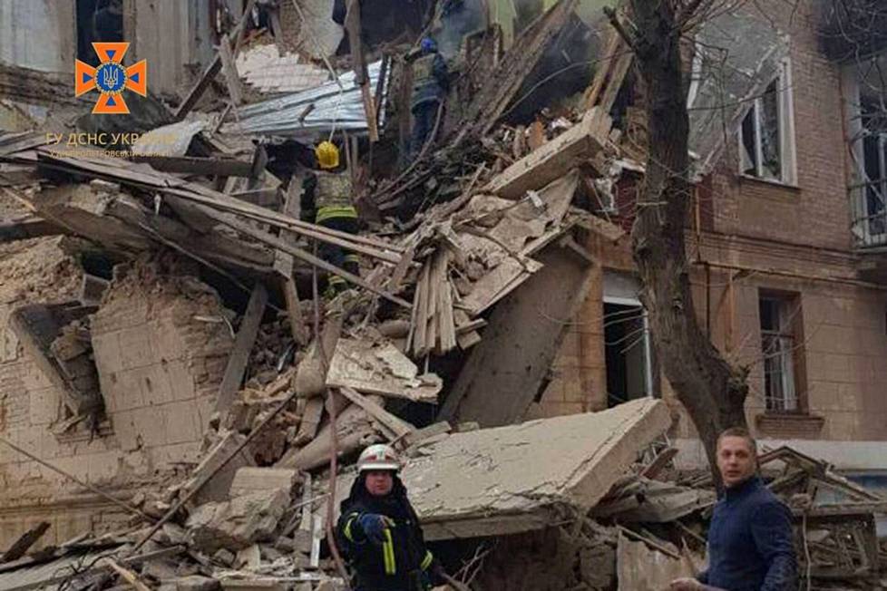 Ukrainan pelastustyöntekijöitä Venäjän iskussa tuhoutuneen rakennuksen edessä Kryvyi Rihissä perjantaina.