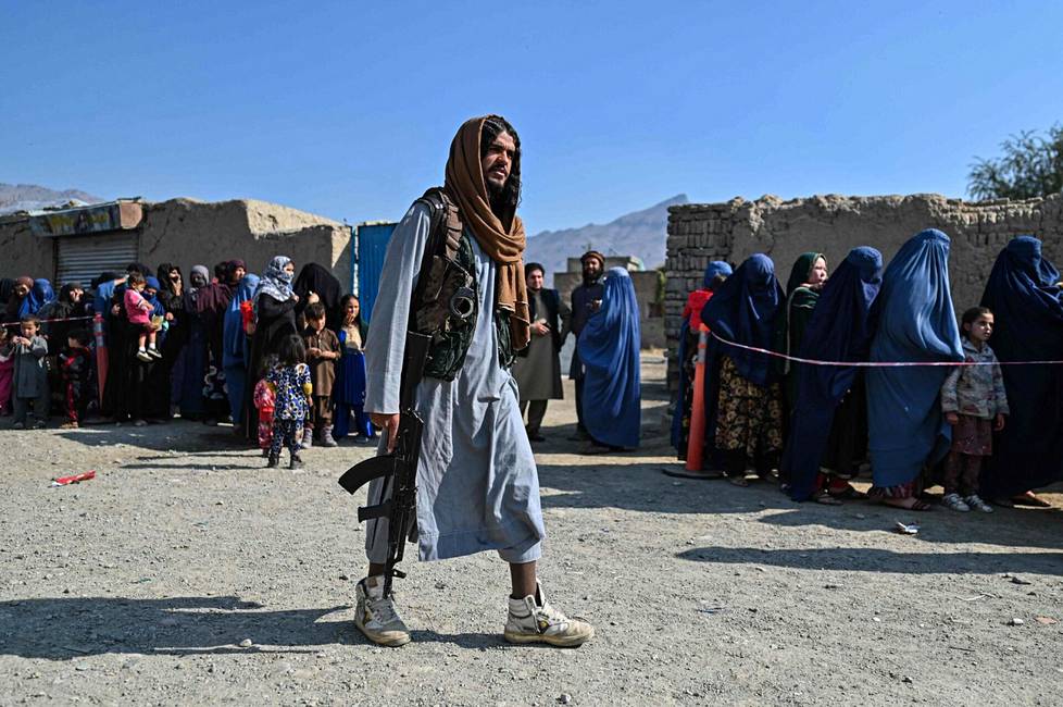Taleban-joukkoihin kuuluva mies valvoi avustusruoka-annoksien jakelua naisille Kabulin laitamilla marraskuussa 2021.