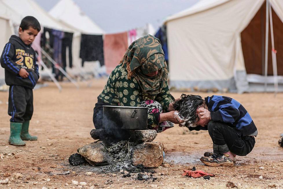 Kotoaan paennut syyrialaisnainen pesi poikansa hiuksia keskiviikkona telttaleirillä Ma’arrat Masrinin kylässä Idlibin maakunnassa. Idlibiä on kuvailtu sodan viimeiseksi loukuksi, jonka Syyrian hallitus lopulta murskaa.