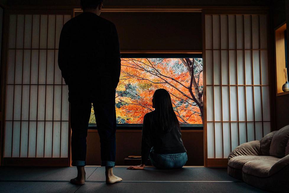 Japanilainen pariskunta perinteisessä japanilaisasunnossa syksyistä luontoa ihailemassa.
