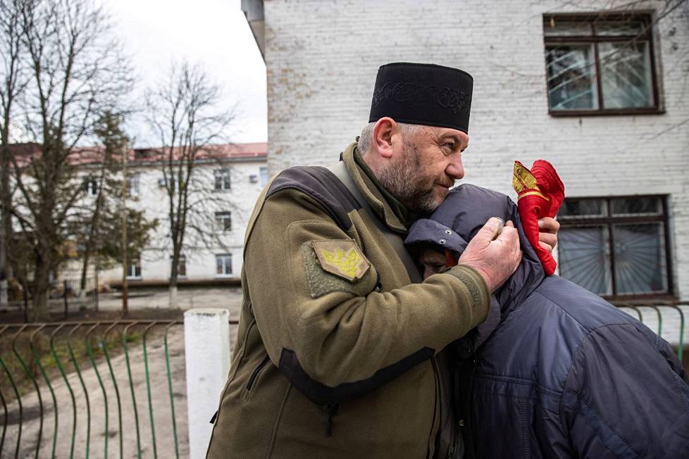 Military pastor Mykola Medinski comforts Mrs. Masha, who is crying out in Bocha. 