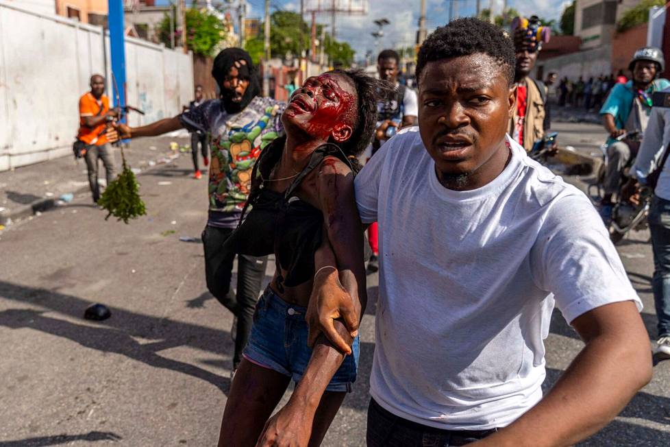 10. lokakuuta. Mies avustaa loukkaantunutta naista Haitin pääministeri Ariel Henryn vastaisten mielenosoitusten aikana Haitissa.
