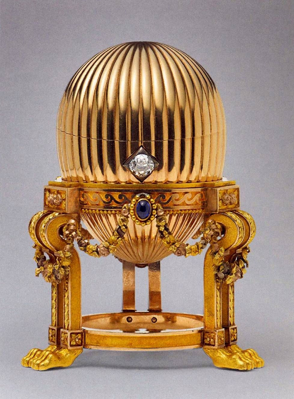 Kolmas keisarillinen pääsiäismuna (1886–87), kultaa, safiireja, timantteja. Arvokkaan kelloyllätyksen sisältävä muna valmistettiin suomalaisen August Holmströmin työhuoneella. Yhdysvaltalaisen romukauppiaan hallussa oleva muna myytiin sittemmin Wartskin kautta, V&A-näyttelyluettelon mukaan jopa noin 20 miljoonalla punnalla. Yksityisomistuksessa. – V&A-näyttelyn katalogin kuvitusta.