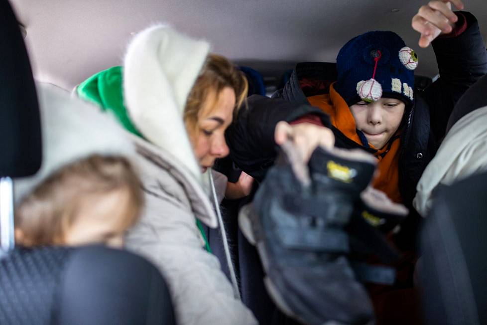 Жанна Пастушенко и двое ее детей Фрося и Матвей размещают багаж на заднем сидении.