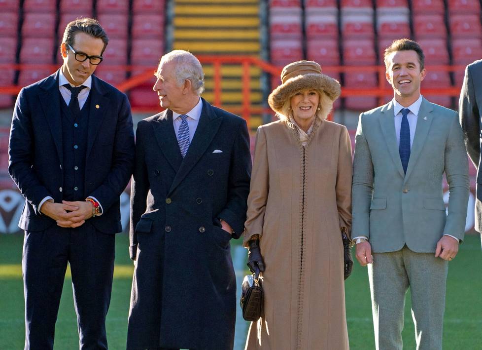 Kuningas Charles ja kuningatar Camilla vierailulla Wrexhamissa joulukuussa. Mukana seuran omistajat Ryan Reynolds (vas.) ja Rob McElhenney (oik.). Alueella riittää brittimonarkian vastustajia.