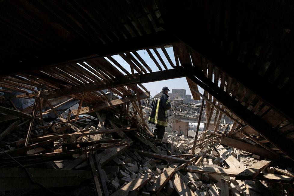 Pelastushenkilökunnanjäsen seisoi tuhoutuneen hallintorakennuksen katolla Harkovassa.