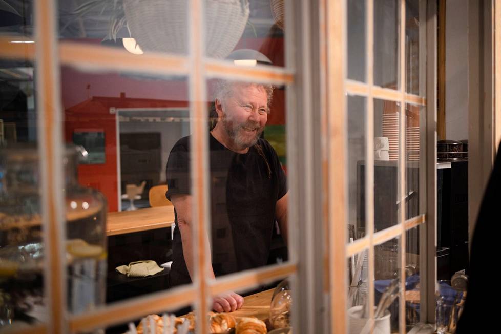 Tuottaja Marko Äijö katsoo ulos kahvila Moosen ikkunasta. Ikkunan takana olevaan kankaaseen on painettu kaupunkinäkymä. Kankaassa on jopa pieniä led-valoja iltavalaistukselle.