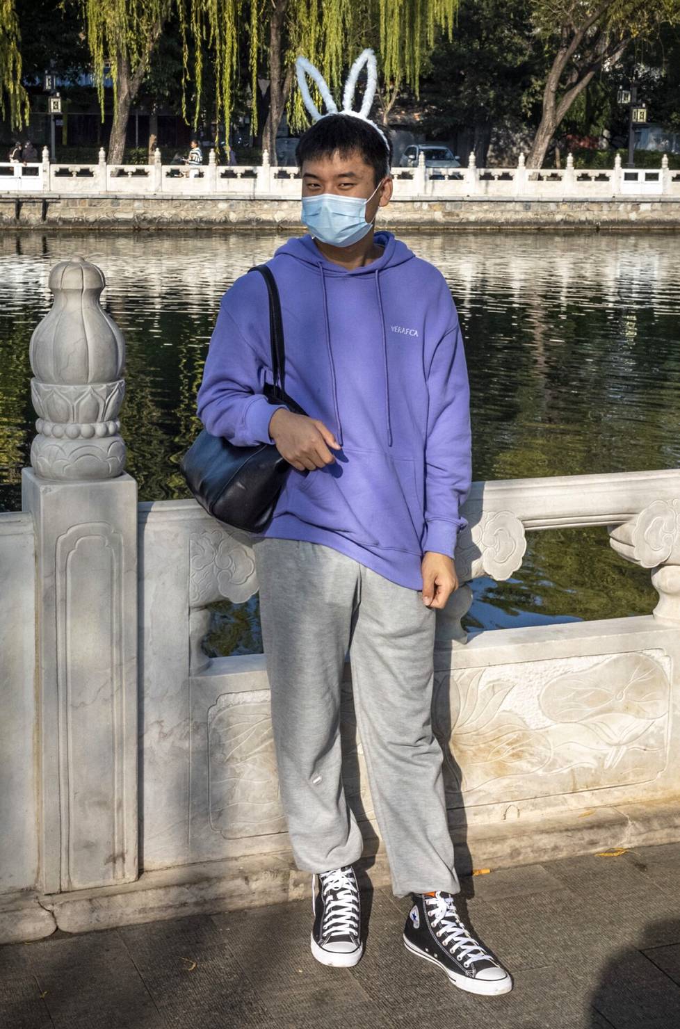 Pupunkorviin pukeutunut poikaystävä kantaa tyttöystävänsä käsilaukkua Pekingissä.