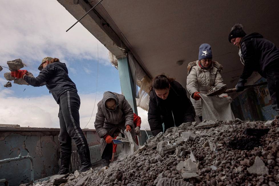 Naiset raivaavat roskia koulusta, joka vaurioitui pommituksissa Harkovassa.