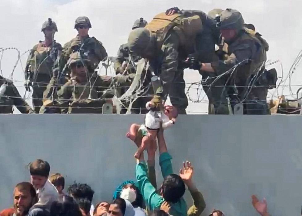 Evakuointilennolle pyrkivät ojensivat lapsensa piikkilanka-aidan ylitse amerikkalaiselle sotilaalle.
