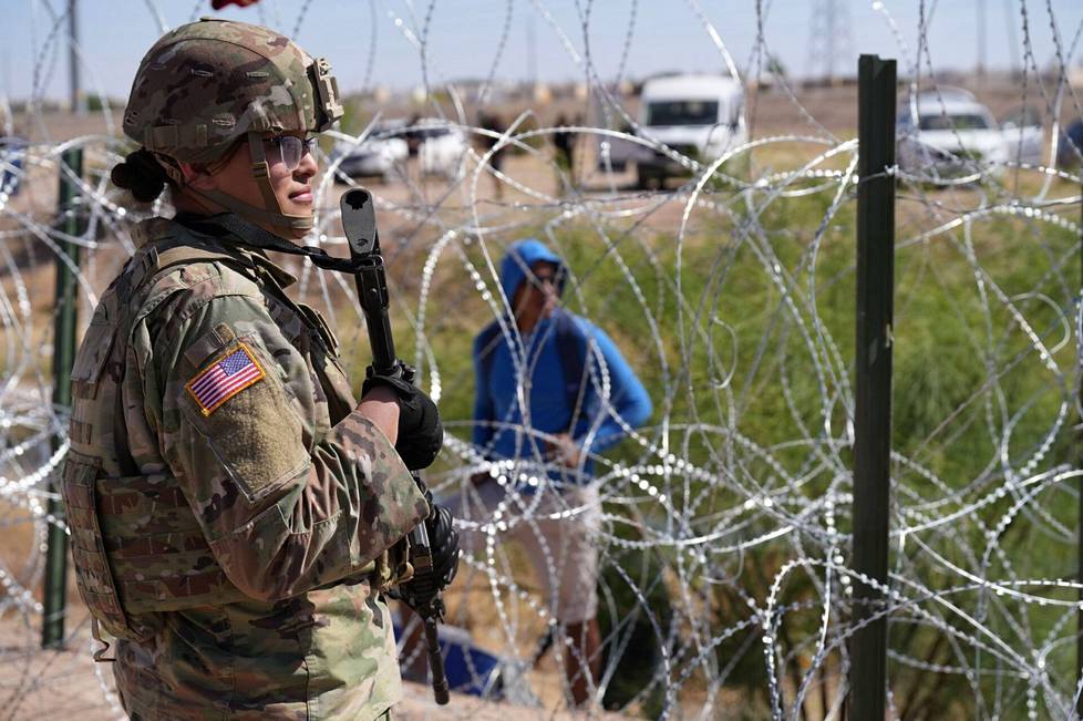 A border guard and an aspirant looked at each other through a barbed wire fence near El Paso, Texas on May 11.