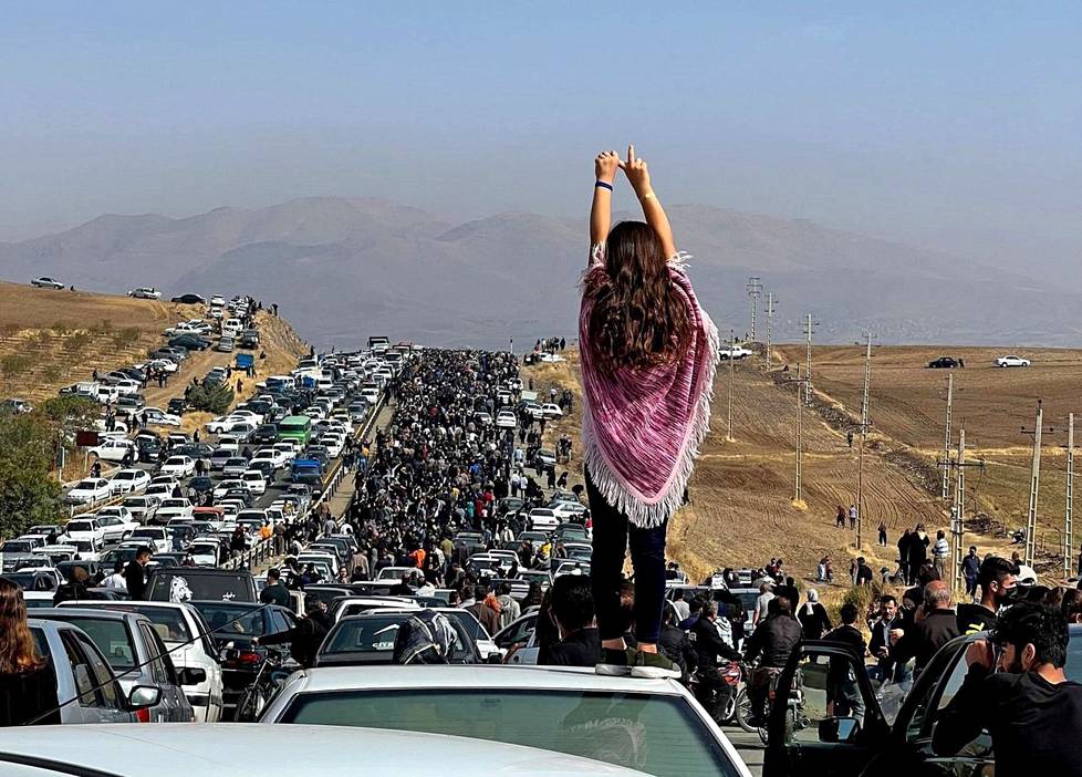 26. lokakuuta. Ilman huntua esiintynyt nainen seisoo auton katolla  tuhansien ihmisten matkatessa kohti Aichin hautausmaata Saqezissa, Länsi-Iranissa, Mahsa Aminin kotikaupungissa 40 päivää poliisin käsiin kuolleen Aminin kuoleman jälkeen.