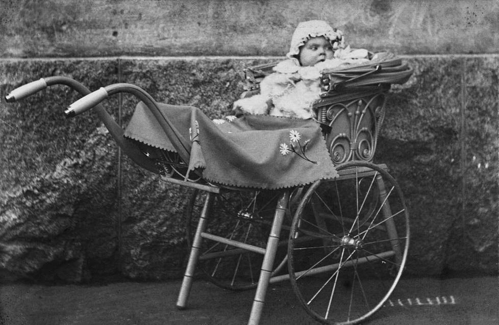 Tyttövauva koristeellisissa lastenvaunuissa vuonna 1906.