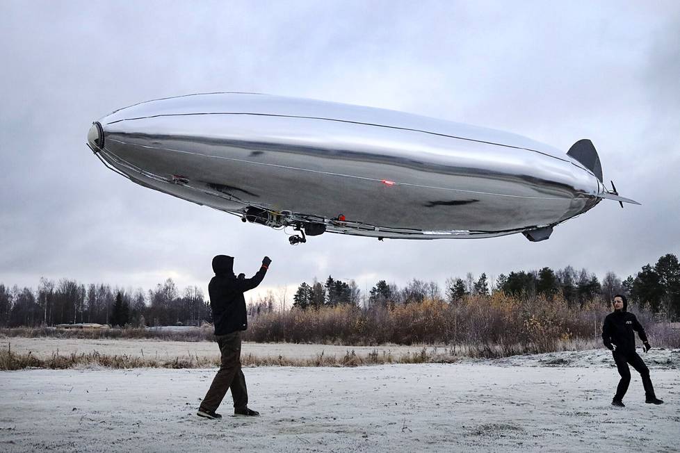 Aircraft engineer Jean-Paul Henderson and flight systems designer Benedek Prágai flew the airship behind the factory.  The people at the airship factory are international: Henderson is a mechanical engineering doctor from New Zealand and Prágai is a Hungarian physicist. 
